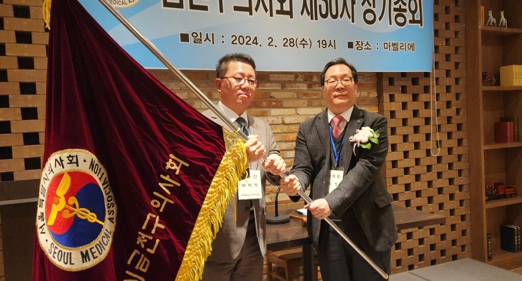 금천구의사회 전동찬 신임회장(왼쪽)이 김덕환 전임회장으로부터 구의사회 깃발을 전달받고 있다