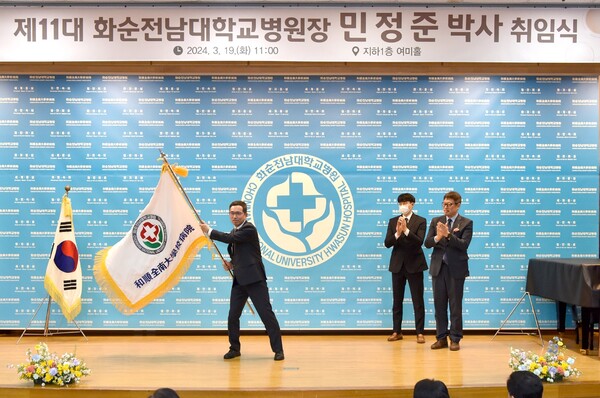 민정준 화순전남대병원장이 정 신 전남대병원장(오른쪽)에게 인계받은 병원기를 흔들고 있다.